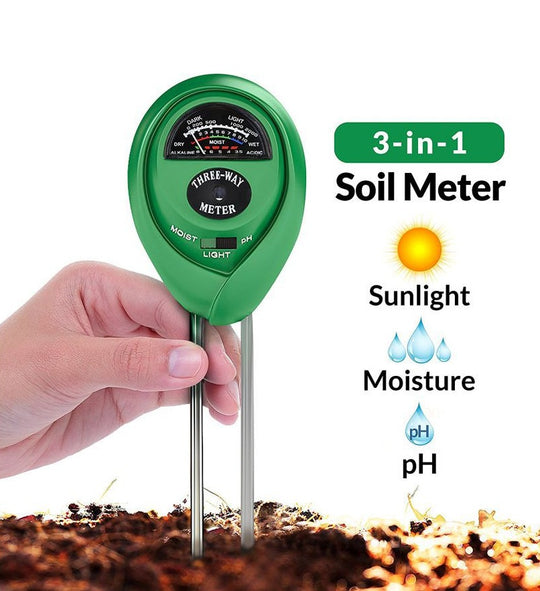 Green 3-in-1 soil meter held by a hand with soil background