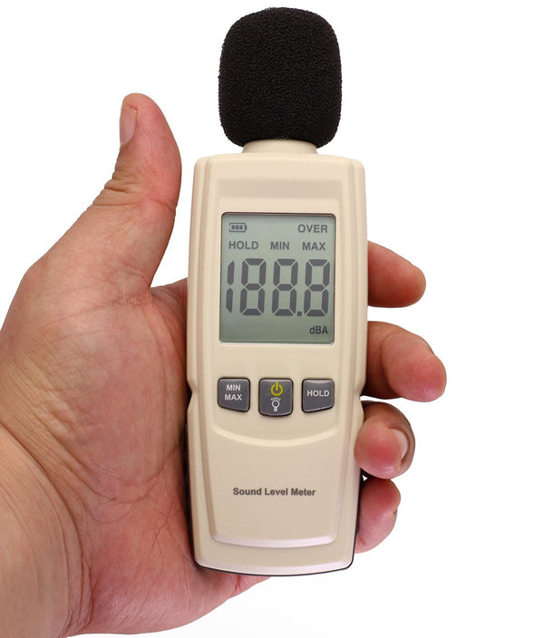 Hand holding a sound level meter with digital display on a white background